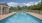 a swimming pool with a deck and chairs and trees in the background